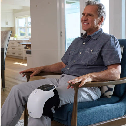 Man using the AuraKnee Pro on his knee while seated at home